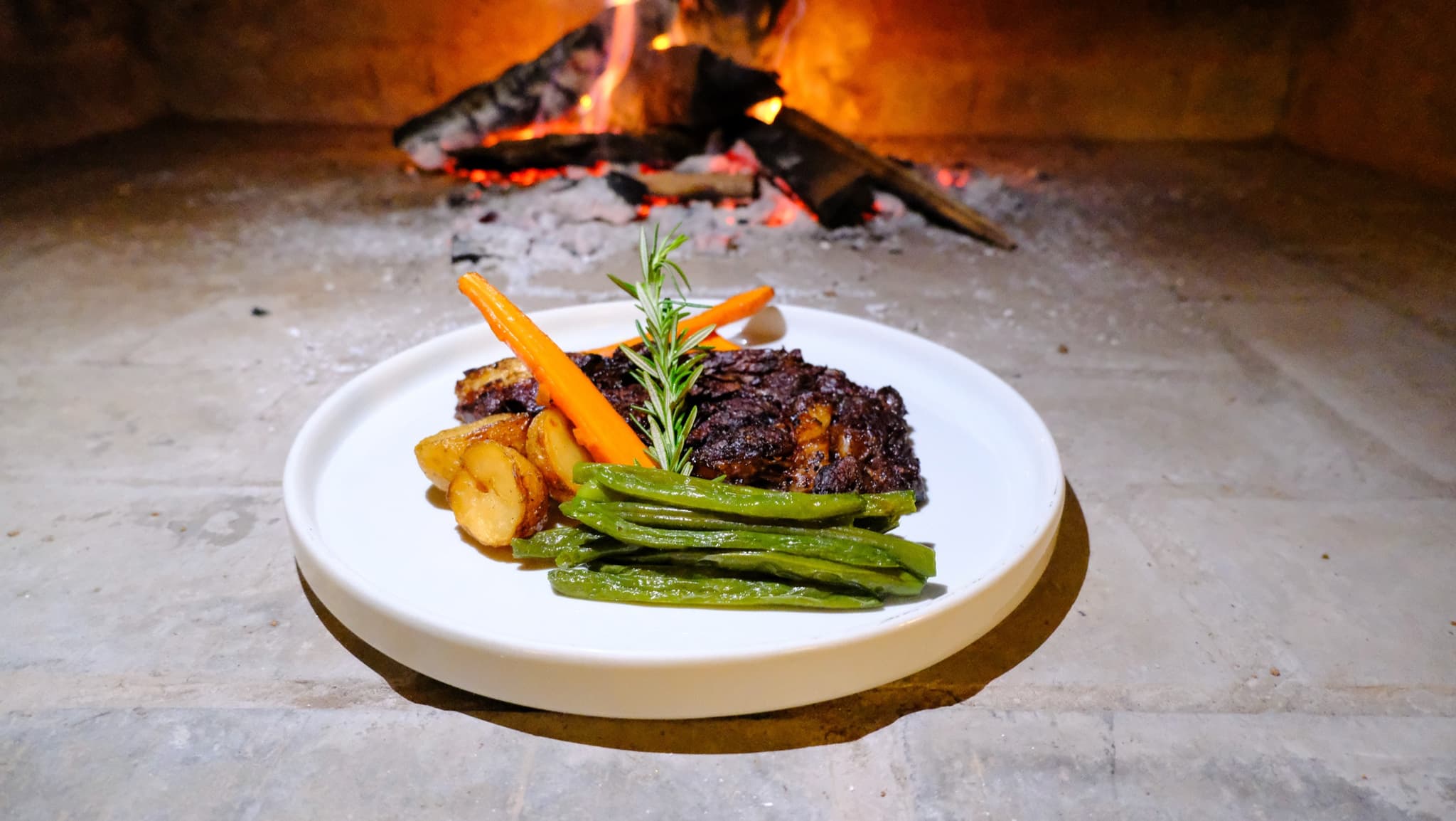 Braised meat with roast potatoes and green beans by the fire