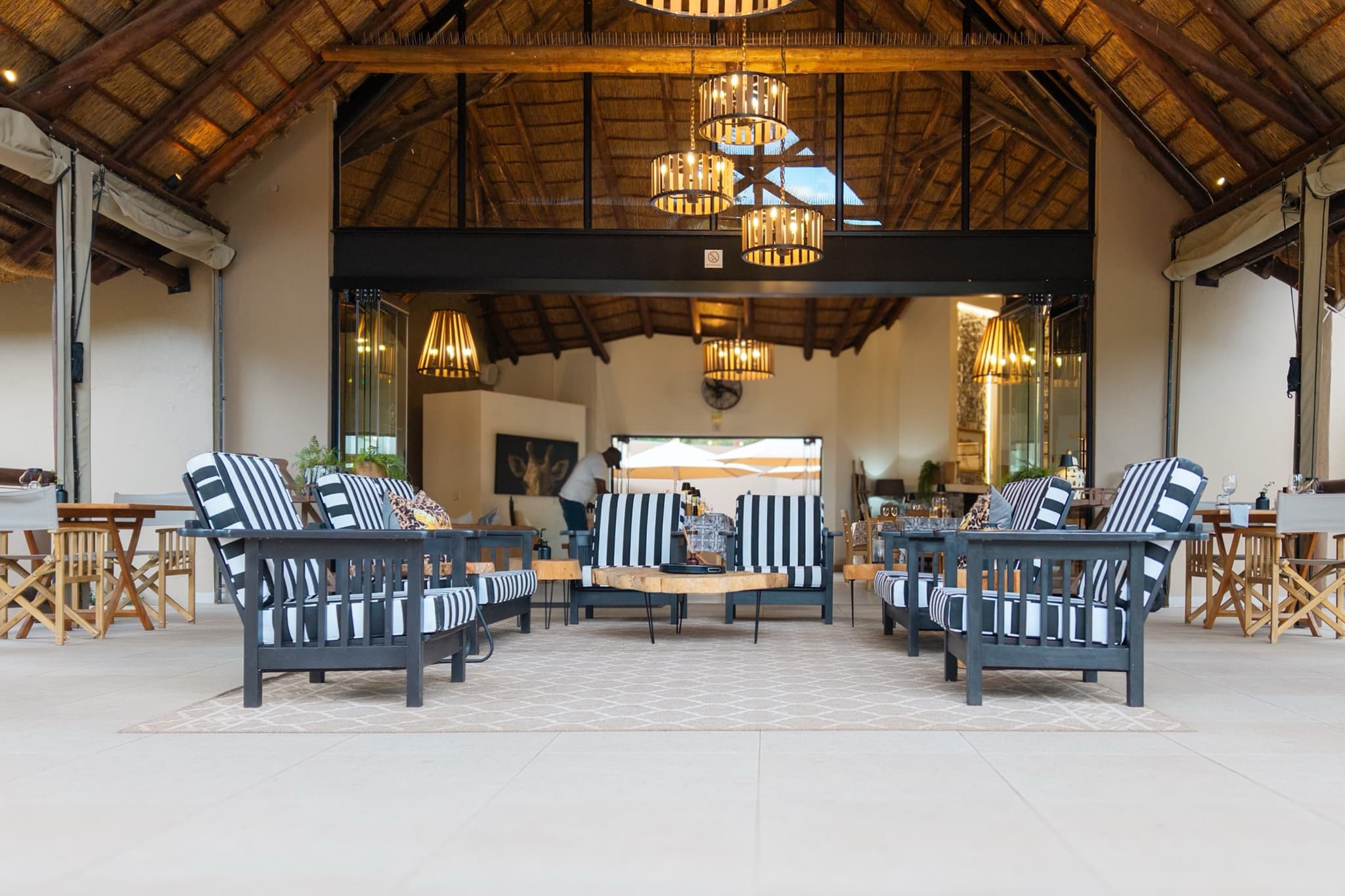 Main lounge and bar with striped chairs and thatch chandeliers